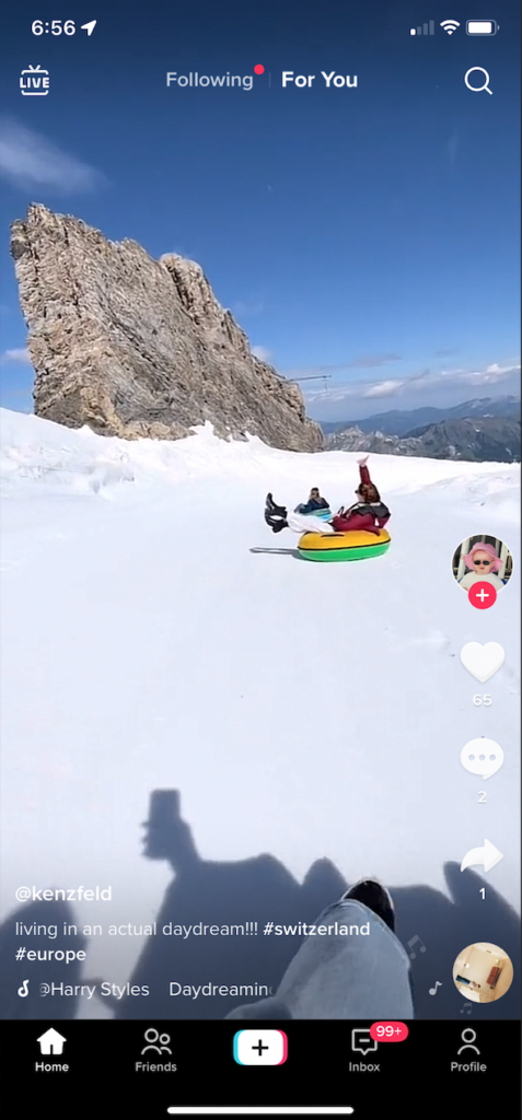 iPhone Screenshot of my TikTok feed depicting a person filming their friends as they tube down the side of a mountain.